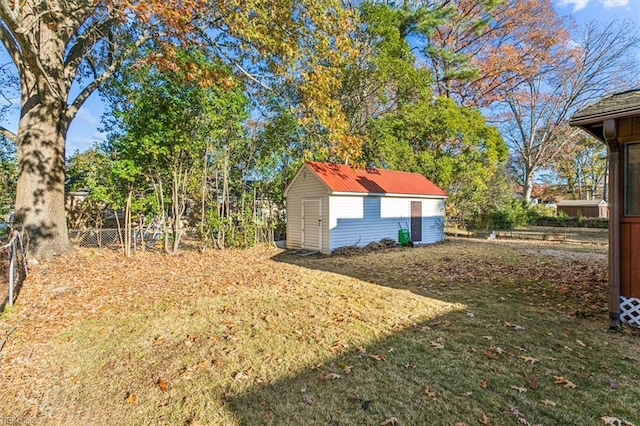 view of yard featuring a shed, fence, and an outbuilding