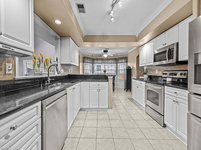 kitchen with a tray ceiling, light tile patterned floors, stainless steel appliances, visible vents, and a sink