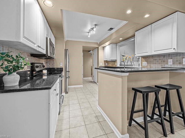 kitchen with light tile patterned floors, stainless steel appliances, a breakfast bar, a peninsula, and white cabinetry