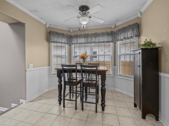 dining area with light tile patterned floors, a textured ceiling, and wainscoting