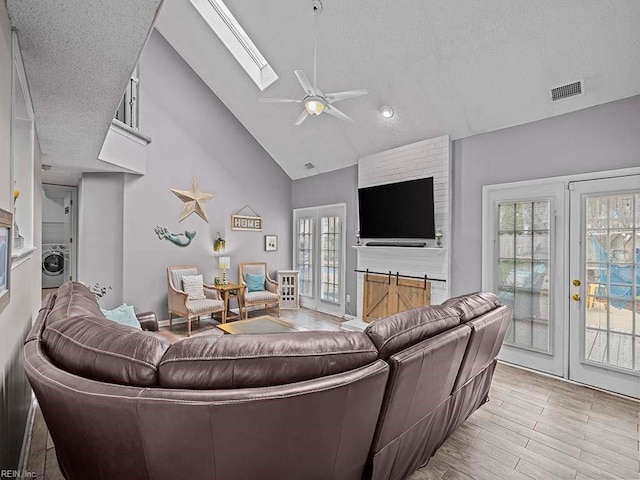 living room with light wood-style flooring, a skylight, visible vents, french doors, and washer / dryer