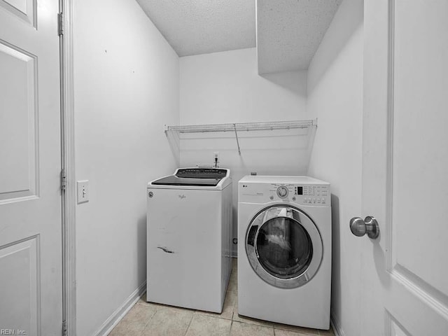 clothes washing area featuring laundry area, baseboards, independent washer and dryer, a textured ceiling, and light tile patterned flooring