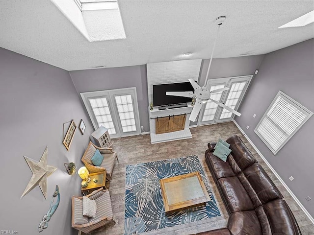 living room featuring a skylight, baseboards, and a textured ceiling