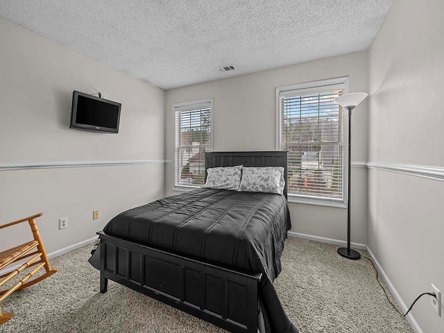 carpeted bedroom with visible vents, a textured ceiling, and baseboards