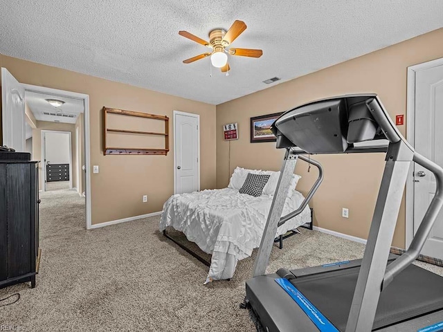 carpeted bedroom with a textured ceiling, a ceiling fan, visible vents, and baseboards