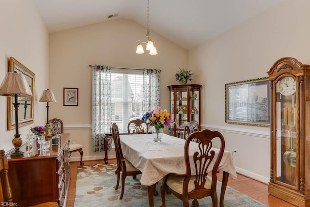 dining area featuring lofted ceiling, a notable chandelier, visible vents, baseboards, and light wood finished floors