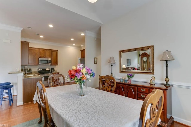 dining area with ornamental molding, light wood finished floors, baseboards, and recessed lighting