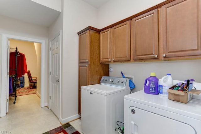 laundry area featuring washing machine and clothes dryer, cabinet space, and baseboards