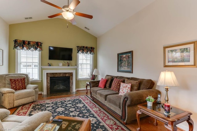 living room featuring lofted ceiling, ceiling fan, wood finished floors, and visible vents