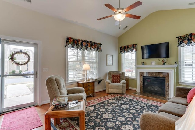 living area featuring a ceiling fan, lofted ceiling, a healthy amount of sunlight, and a premium fireplace