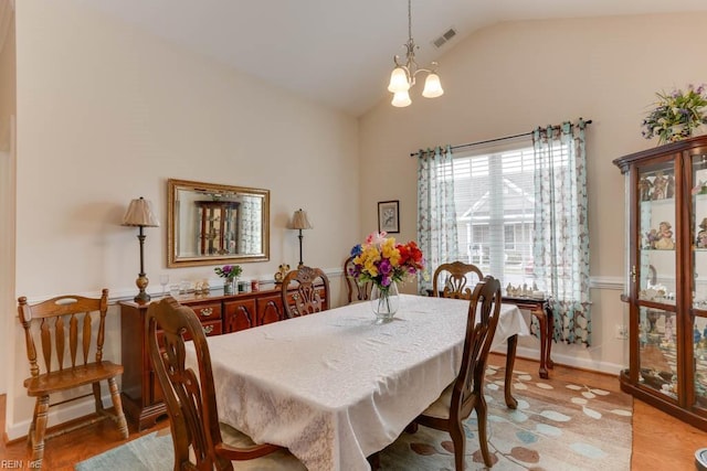 dining room with lofted ceiling, visible vents, a chandelier, light wood-type flooring, and baseboards