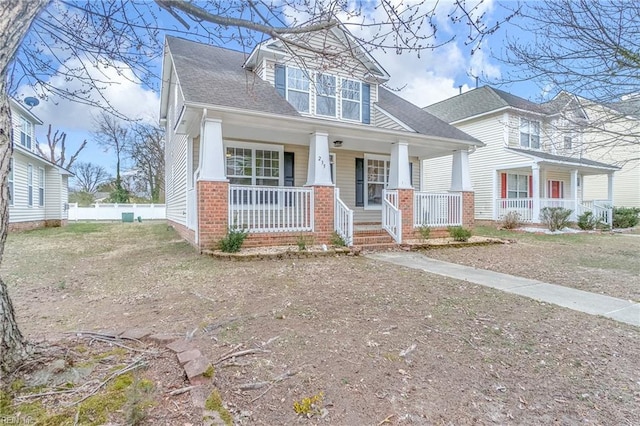 view of front of home featuring covered porch, a shingled roof, and fence