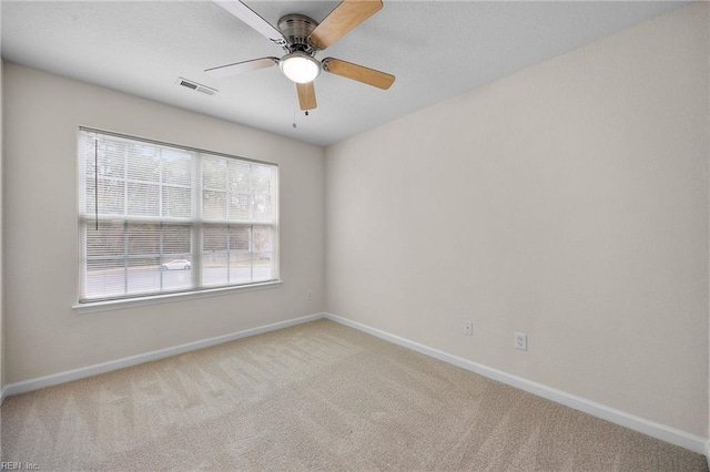 carpeted spare room with baseboards, visible vents, ceiling fan, and a textured ceiling