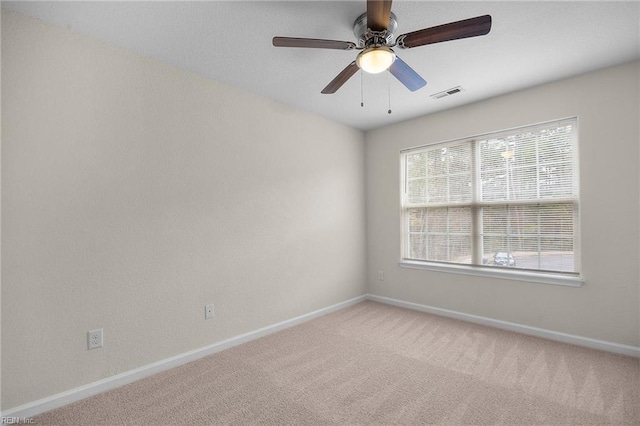 empty room with carpet, visible vents, ceiling fan, and baseboards