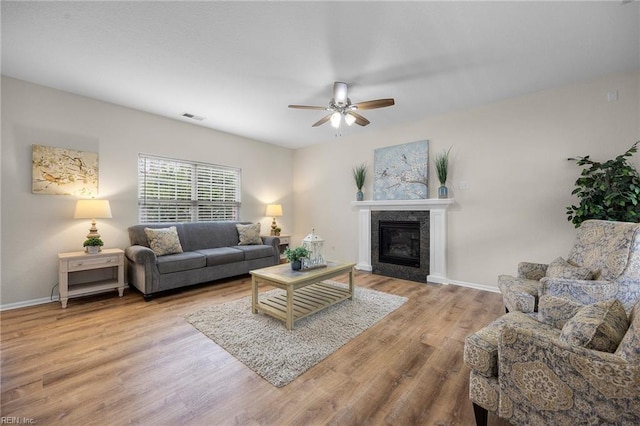 living room featuring baseboards, visible vents, wood finished floors, and a tile fireplace