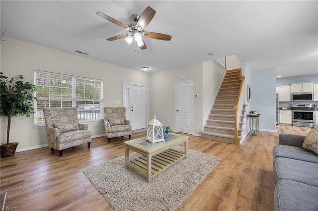 living area featuring baseboards, stairway, visible vents, and light wood-style floors