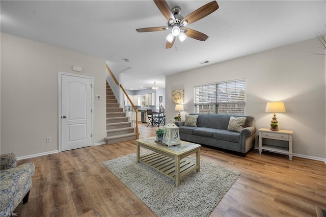 living area with stairs, wood finished floors, visible vents, and baseboards