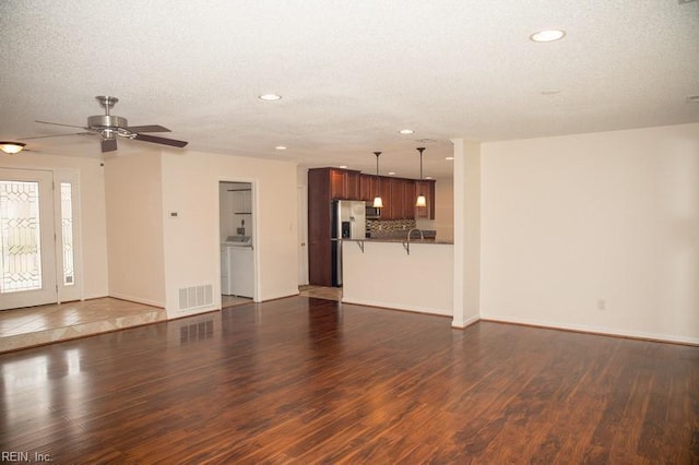 unfurnished living room with baseboards, visible vents, dark wood finished floors, a textured ceiling, and recessed lighting