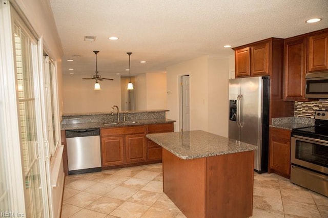 kitchen with decorative backsplash, appliances with stainless steel finishes, brown cabinetry, a sink, and dark stone counters