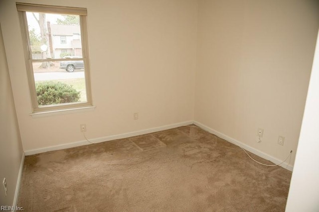 empty room featuring carpet and baseboards