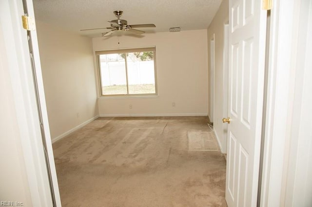 unfurnished room with a textured ceiling, baseboards, visible vents, and light colored carpet