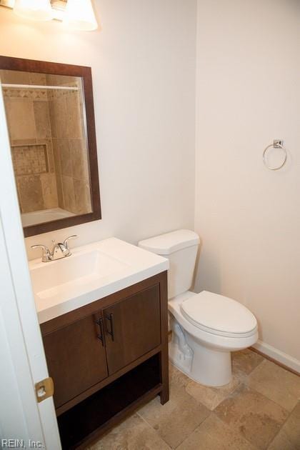 bathroom with a shower, vanity, toilet, and baseboards