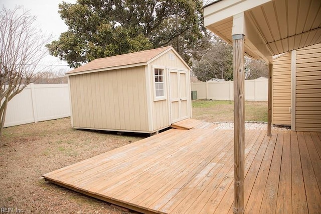 wooden deck with an outbuilding, a fenced backyard, and a shed