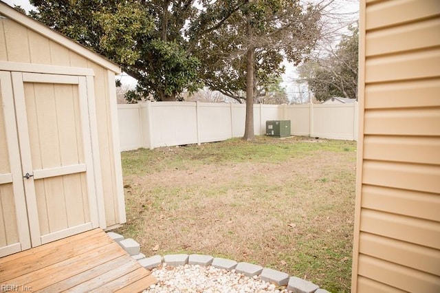 view of yard featuring a fenced backyard, a storage unit, and an outbuilding