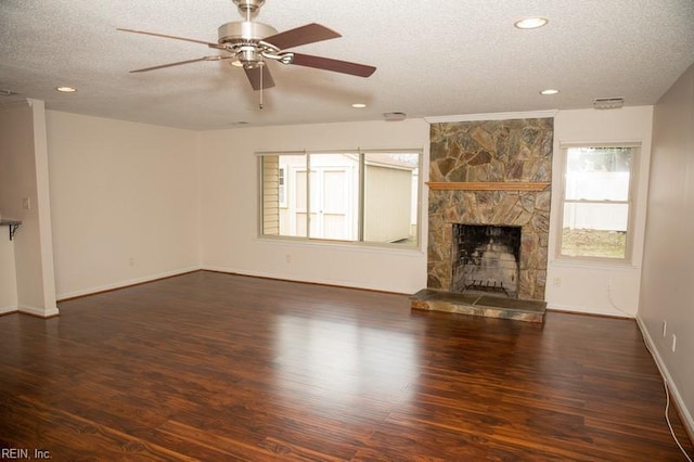 unfurnished living room featuring a fireplace, a textured ceiling, baseboards, and wood finished floors