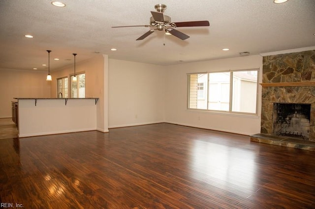 unfurnished living room featuring a fireplace, dark wood finished floors, a textured ceiling, and ceiling fan