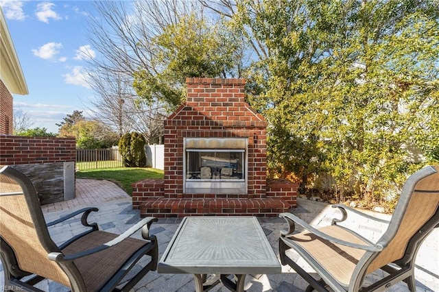 view of patio / terrace with an outdoor brick fireplace and fence