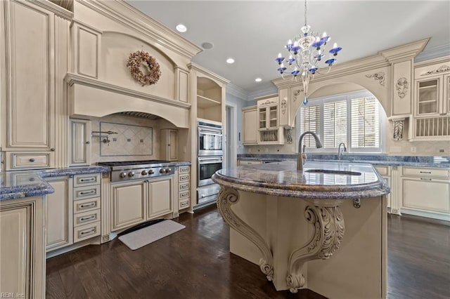 kitchen with dark stone countertops, cream cabinetry, glass insert cabinets, and appliances with stainless steel finishes