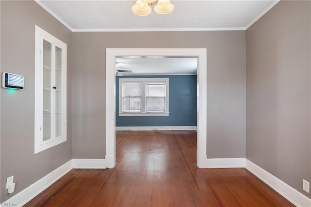 interior space featuring wood-type flooring, a notable chandelier, crown molding, and baseboards