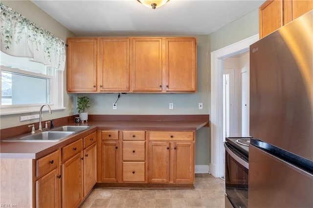 kitchen with freestanding refrigerator, electric stove, and a sink