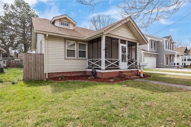 view of front of property with a garage, a sunroom, roof with shingles, fence, and a front yard