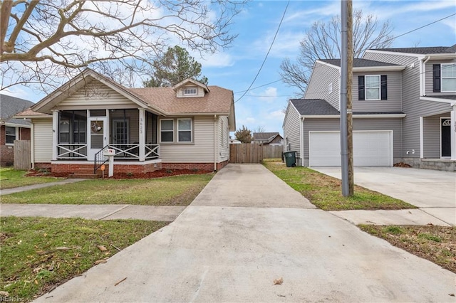 view of front of property with a garage, concrete driveway, a sunroom, fence, and a front yard