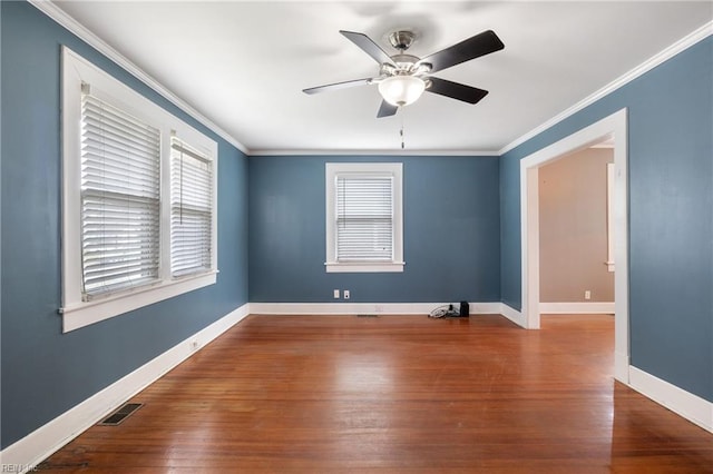 unfurnished room featuring baseboards, wood finished floors, a wealth of natural light, and crown molding