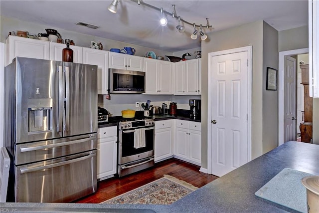 kitchen with dark wood-style flooring, visible vents, white cabinets, appliances with stainless steel finishes, and dark countertops