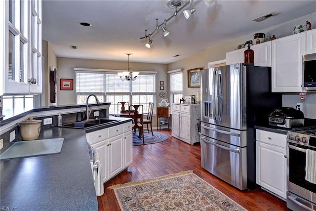 kitchen featuring stainless steel appliances, dark wood-style flooring, a sink, white cabinets, and dark countertops