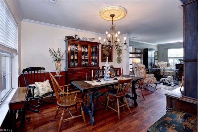 dining area with ornamental molding, a notable chandelier, and hardwood / wood-style floors