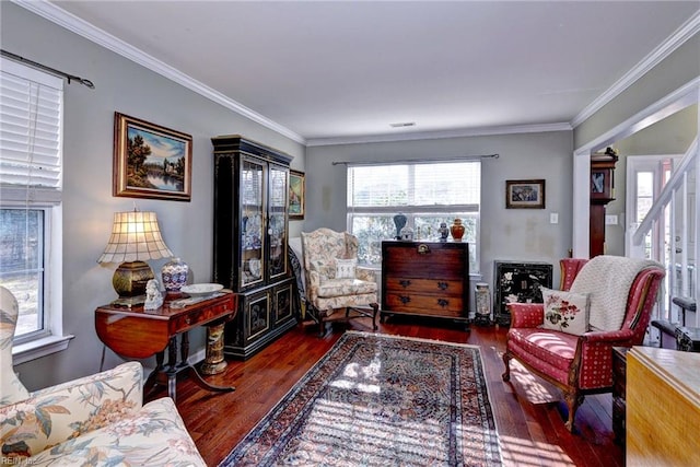 living area featuring hardwood / wood-style floors, stairway, visible vents, and crown molding