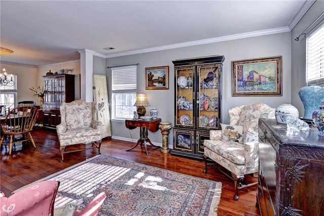 living area with a healthy amount of sunlight, crown molding, a notable chandelier, and hardwood / wood-style floors