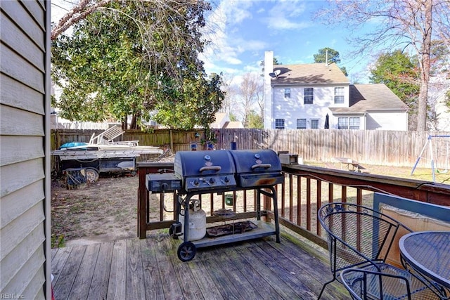 wooden terrace with a fenced backyard and a grill