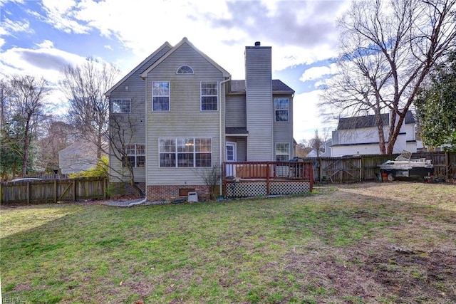 rear view of house featuring a yard, a chimney, a fenced backyard, and a wooden deck