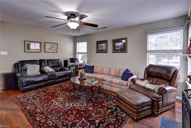 living room with wood-type flooring, visible vents, ceiling fan, and baseboards