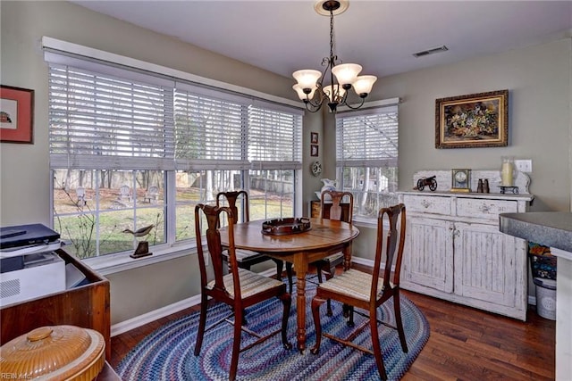 dining room featuring dark wood-type flooring, a wealth of natural light, visible vents, and a notable chandelier