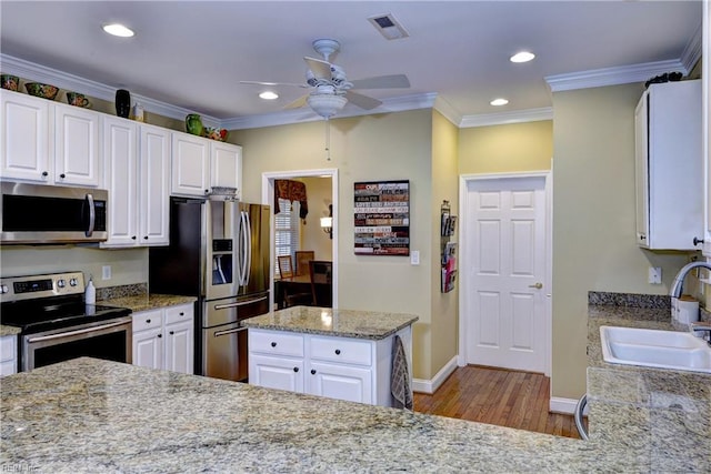 kitchen with visible vents, appliances with stainless steel finishes, ornamental molding, white cabinets, and a sink