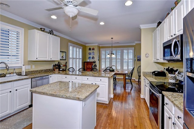 kitchen featuring crown molding, a wealth of natural light, appliances with stainless steel finishes, a sink, and a peninsula