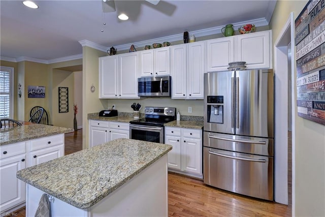 kitchen with white cabinetry, ornamental molding, stainless steel appliances, and light wood-style flooring