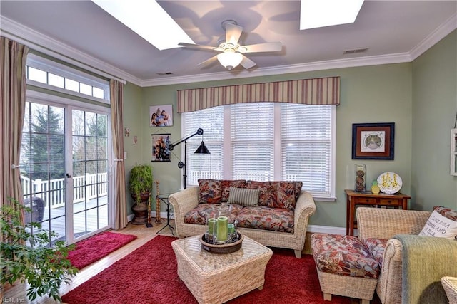 living area featuring a skylight, visible vents, and crown molding